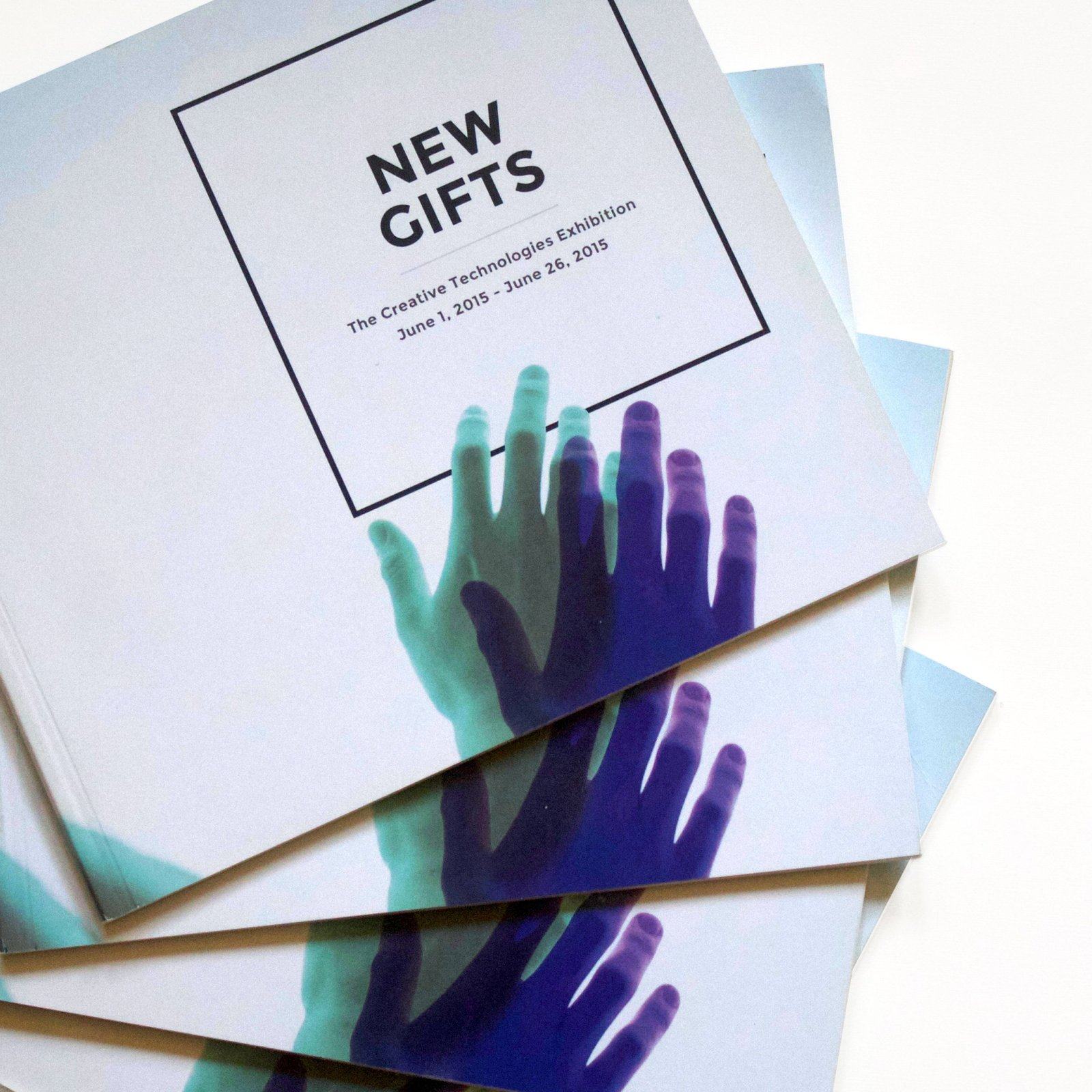 A stack of New Gifts exhibition books showing the cover with overlapping tinted hands
