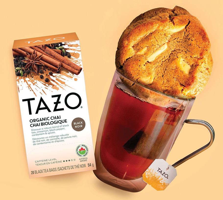 Tazo Organic Chai box beside a glass mug of chai with a chai cookie resting on top